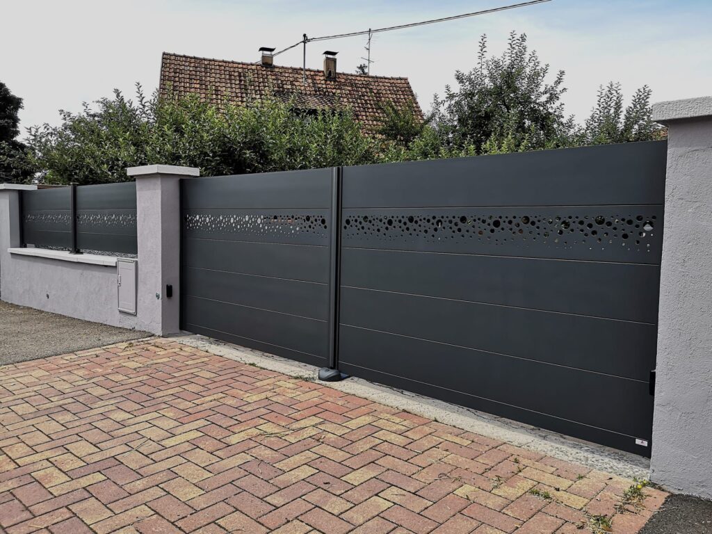 Portail aluminium anthracite à bandeau de cercles découpés sur une entrée pavée, une réalisation d'AS Ouvertures, poseur de portails à Haguenau