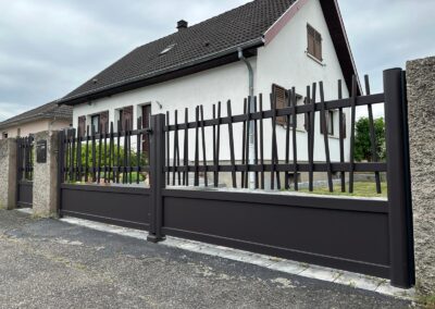 Portail et portillon aluminium brun foncé à barreaudage irrégulier, entre piliers crépis